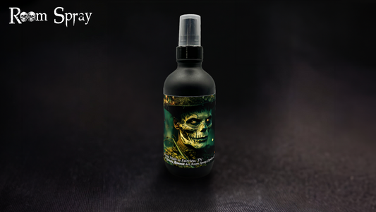 A black bottle of 'The Witch Doctor' room spray with a label featuring a skull and green leaves, indicating a spicy and smoky fragrance.